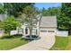 Charming two-story home with a manicured lawn, mature trees, a paved driveway, and an attached two-car garage at 1095 Northpoint Trce, Roswell, GA 30076
