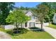 Charming two-story home featuring lush green lawn, mature shade trees, a paved driveway, and an attached garage at 1095 Northpoint Trce, Roswell, GA 30076