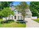 Charming two-story home with a well-manicured lawn, lush trees, a paved driveway, and an attached garage at 1095 Northpoint Trce, Roswell, GA 30076