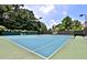 View of well maintained tennis courts with lighting and a fence and lush trees surrounding the court at 15 Vickwood Court Ne, Marietta, GA 30068