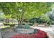 Entrance to condo community with stone signage, colorful flowers, and mature shade trees at 4604 Vinings Central Se Run # 131, Atlanta, GA 30339