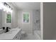 Updated bathroom featuring a marble tiled tub, modern fixtures, and natural lighting at 772 Brookwood Sw Ter, Lilburn, GA 30047