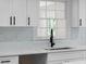 Close-up of bright kitchen featuring white cabinets, quartz countertops, black hardware, and subway tile backsplash at 772 Brookwood Sw Ter, Lilburn, GA 30047
