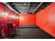 Unfinished basement with a platform stage, red walls, dark carpet, and exposed ceiling at 10119 Azalea Dr, Covington, GA 30014