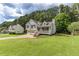 View of a charming two-story home with an expansive lawn and mature trees, creating a serene, inviting atmosphere at 1049 Braddock Cir, Woodstock, GA 30189