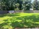 View of green backyard featuring a privacy fence, shed, and wooded area at 1725 Spindle Top Sw Ct, Lilburn, GA 30047