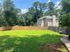 Large green backyard with a playset, privacy fence, and wooded area at 1725 Spindle Top Sw Ct, Lilburn, GA 30047