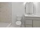 Bright bathroom featuring a tiled shower, modern vanity, toilet, and decorative mirror, enhanced by neutral tiling at 4103 Statewood Ne Rd, Atlanta, GA 30342