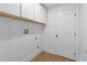 Clean, simple laundry room with white cabinets, white walls, and a door, with light colored floors at 4103 Statewood Ne Rd, Atlanta, GA 30342