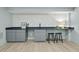 Basement wet bar with sleek gray cabinets, black countertop, tiled backsplash, and modern stools for entertaining at 4103 Statewood Ne Rd, Atlanta, GA 30342