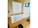 Bright bathroom showcasing a tiled tub, neutral decor, and a window for natural light at 5771 Vinings Retreat Sw Way, Mableton, GA 30126