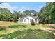 Expansive backyard with lush green grass, surrounded by mature trees, and a charming white house with a fenced perimeter at 136 Fairlane Dr, Covington, GA 30016