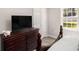 Well-lit bedroom featuring a large dresser with a TV and a view from the window at 136 Fairlane Dr, Covington, GA 30016