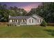 Charming single-story home featuring a cozy front porch, green lawn and landscaped garden at 136 Fairlane Dr, Covington, GA 30016