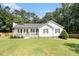Charming single-story home featuring a cozy front porch, green lawn and landscaped garden at 136 Fairlane Dr, Covington, GA 30016