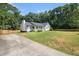 Quaint home featuring a well-manicured lawn, inviting front porch, mature trees, and long driveway at 136 Fairlane Dr, Covington, GA 30016