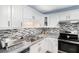 Well-lit kitchen with stainless steel appliances, white cabinets, and decorative backsplash at 136 Fairlane Dr, Covington, GA 30016