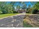 Long driveway leading to a brick home with an attached garage, surrounded by mature trees and a lush lawn at 5148 Coolamber Dr, Powder Springs, GA 30127