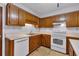 Galley kitchen features wood cabinets, white appliances and tile flooring at 5148 Coolamber Dr, Powder Springs, GA 30127