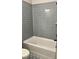 Modern bathroom with gray tiled walls, white tub, and decorative flooring at 7220 Winderlea Ln, Cumming, GA 30040