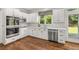 Modern kitchen featuring stainless steel appliances, white cabinets, wood floors, and tiled backsplash at 4345 Mantle Ridge Dr, Cumming, GA 30041