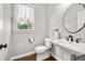 Charming powder room featuring pedestal sink, decorative mirror, elegant fixtures, and hardwood flooring at 4345 Mantle Ridge Dr, Cumming, GA 30041
