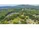 Aerial view of homes nestled among lush trees and green fields, with mountains in the background at 1480 Bettis Tribble Gap Rd, Cumming, GA 30040