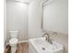 Bathroom featuring modern sink, toilet, white cabinet, and wood-look flooring at 1480 Bettis Tribble Gap Rd, Cumming, GA 30040
