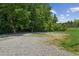 Large gravel lot with trees in the background, offering ample space for parking or potential development at 1480 Bettis Tribble Gap Rd, Cumming, GA 30040
