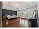 Large bedroom features a tray ceiling, wainscoting, hardwood floors, and a grand chandelier at 236 Lakestone Pkwy, Woodstock, GA 30188