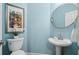Stylish powder room featuring a pedestal sink, round mirror, and modern fixtures with light blue walls at 1345 Benbrooke Nw Ln, Acworth, GA 30101