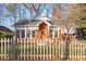 View of the front exterior with brick, roof, and windows surrounded by trees, foliage, and a wooden fence at 1015 Deckner Sw Ave, Atlanta, GA 30310