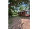 Exterior view of single-story home with brick siding, green metal roof, and partially wooded lot at 10591 Flat Shoals Rd Rd, Covington, GA 30016