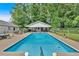 Backyard pool with a rectangular shape, surrounded by lush trees, and a white pool house in the background at 146 Henderson Farm Ln, Canton, GA 30115