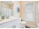 Bright bathroom featuring a white vanity, toilet, tub, and shower combination, with natural light from a large window at 1856 Temple Park Dr, Loganville, GA 30052