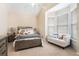 A cozy bedroom features neutral walls and a bed with comfortable bedding, and a sitting area by the window at 1856 Temple Park Dr, Loganville, GA 30052