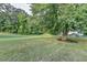Expansive grassy backyard featuring mature trees and a partially wooded perimeter, offering ample outdoor space at 2035 Lena Carter Rd, Buford, GA 30519