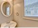 Half bathroom with simple design features a pedestal sink, round mirror, and natural light at 2035 Lena Carter Rd, Buford, GA 30519