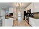 Contemporary kitchen with stainless steel appliances, granite countertops, white cabinetry, and wood-look flooring at 2035 Lena Carter Rd, Buford, GA 30519