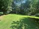 Expansive backyard featuring lush green grass, mature trees, and partial fencing at 975 Willeo Rd, Roswell, GA 30075