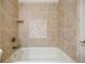 Close-up of tub featuring light brown tiling with decorative tile, and sleek silver faucet and shower head at 1505 Walker Ave, College Park, GA 30337