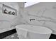 Elegant freestanding bathtub with marble tile surround, a built-in niche, and black hardware at 701 Smith St, Atlanta, GA 30310