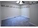 Empty carpeted bedroom featuring an overhead fan and light, and patterned wallpaper border at 7448 Berea Road, Winston, GA 30187