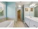 Bright bathroom featuring a double sink vanity, large mirror, soaking tub, and walk-in closet at 8965 Friarbridge Dr, Suwanee, GA 30024