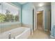 Bathroom with a soaking tub under a window and access to a walk-in closet at 8965 Friarbridge Dr, Suwanee, GA 30024