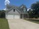 Two-story home featuring a two-car garage, stone accents, and well-manicured lawn at 8965 Friarbridge Dr, Suwanee, GA 30024