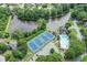 An aerial view showcasing community amenities, including tennis courts, a pool, and a serene pond, all surrounded by trees at 1024 Cromwell Pt, Snellville, GA 30078