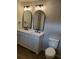Bathroom featuring a double sink vanity, arched mirrors, modern lighting and wood look floors at 2748 Farmstead Ct, Grayson, GA 30017