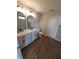 Bathroom featuring a double sink vanity, arched mirrors, modern lighting and wood look floors at 2748 Farmstead Ct, Grayson, GA 30017