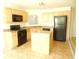Efficient kitchen featuring black appliances, light wood cabinets, and a central island, perfect for culinary enthusiasts at 4232 Kensington Cv, Atlanta, GA 30349